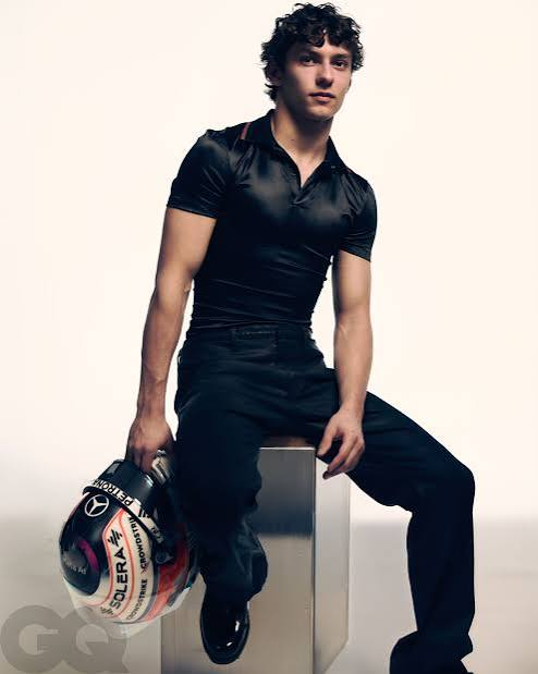 Kimi Antonelli sitting on a metal block holding a helmet